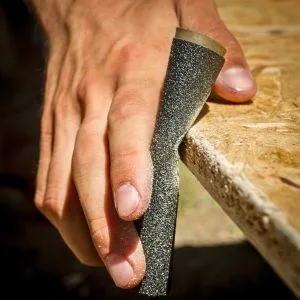 Hand met schuurpapier op tafel"