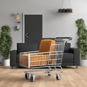 Een winkelwagen met een oranje fauteuil erin, geplaatst in een moderne woonkamer met een zwarte bank, planten en decoratieve elementen aan de muur.